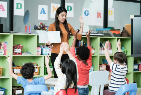 Young asian woman teacher teaching kids in kindergarten classroo