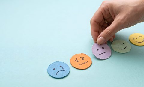Hand placing a purple neutral emotion face icon on a blue background