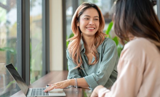 Happy,Asian,Woman,Talking,To,A,Friend,Aside,Laptop,While