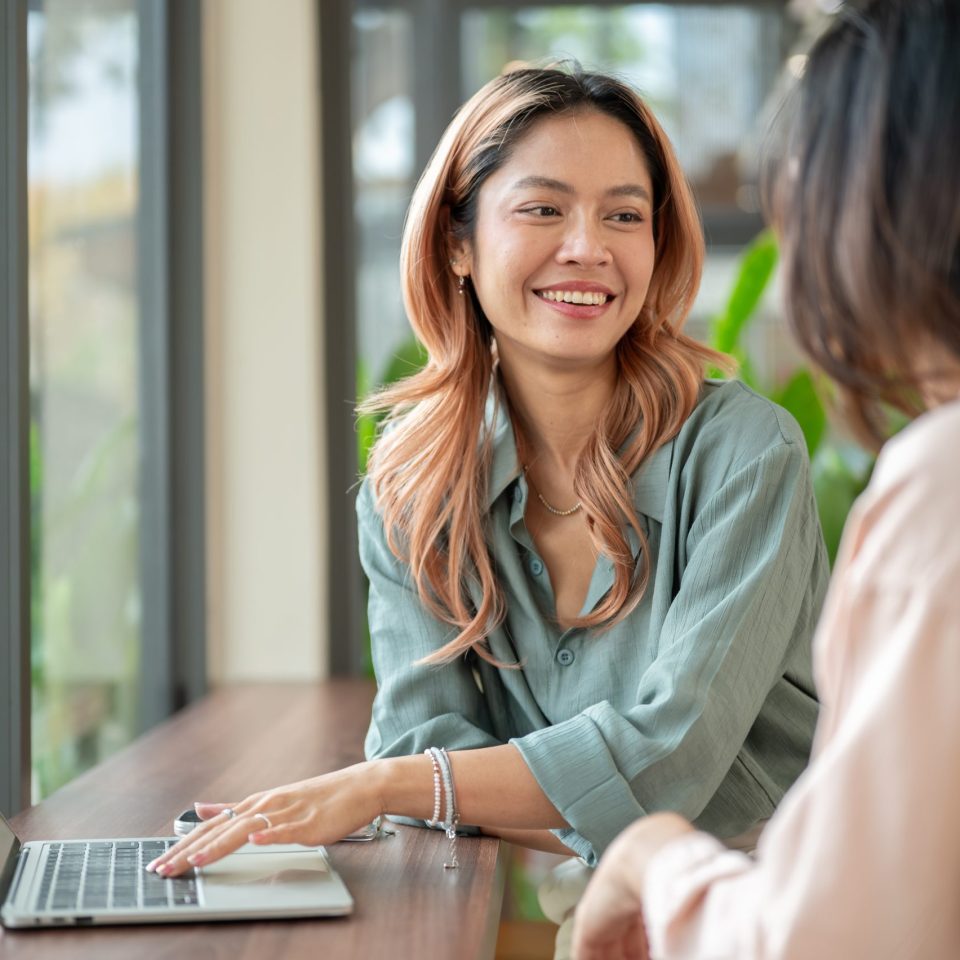 Happy,Asian,Woman,Talking,To,A,Friend,Aside,Laptop,While